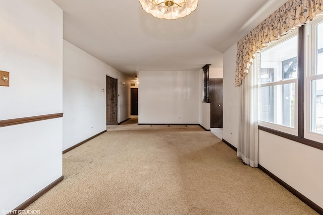 empty room featuring baseboards, carpet floors, and a chandelier