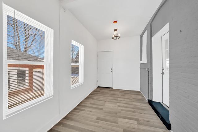 doorway to outside with a notable chandelier and light wood finished floors