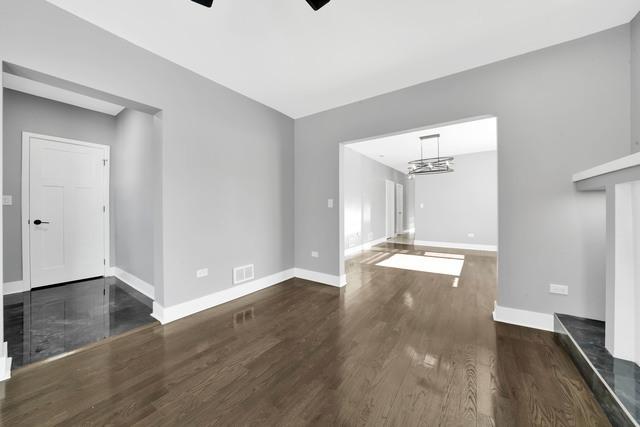 unfurnished living room with visible vents, ceiling fan with notable chandelier, baseboards, and wood finished floors