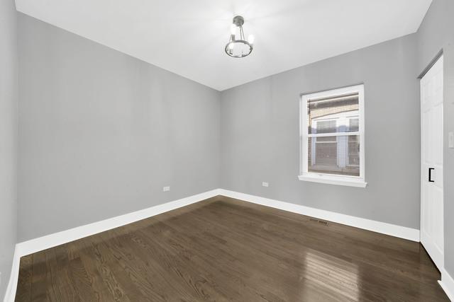 unfurnished room featuring baseboards, an inviting chandelier, and dark wood-style floors