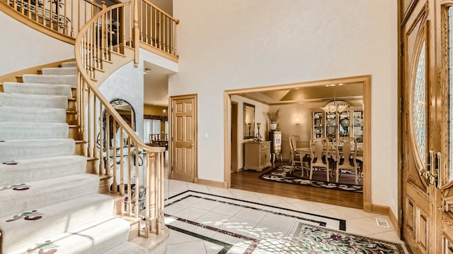 foyer featuring tile patterned flooring, stairway, a high ceiling, and baseboards