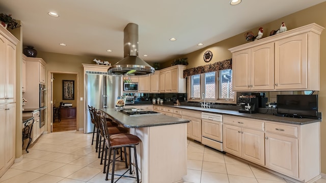kitchen with a breakfast bar, dark countertops, island exhaust hood, and stainless steel appliances