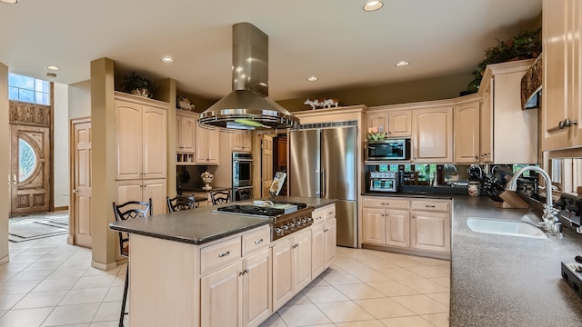 kitchen featuring dark countertops, a kitchen island, appliances with stainless steel finishes, island range hood, and a sink