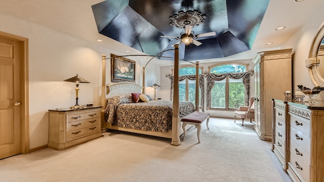 bedroom with recessed lighting, light colored carpet, a raised ceiling, and baseboards