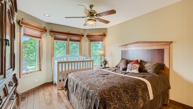 bedroom with light wood finished floors, visible vents, multiple windows, and baseboards