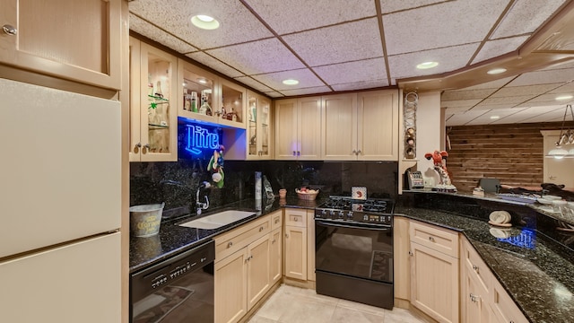 kitchen with decorative backsplash, dark stone countertops, black appliances, and a sink