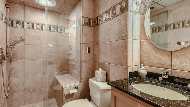 bathroom featuring tile walls, a shower stall, toilet, and vanity