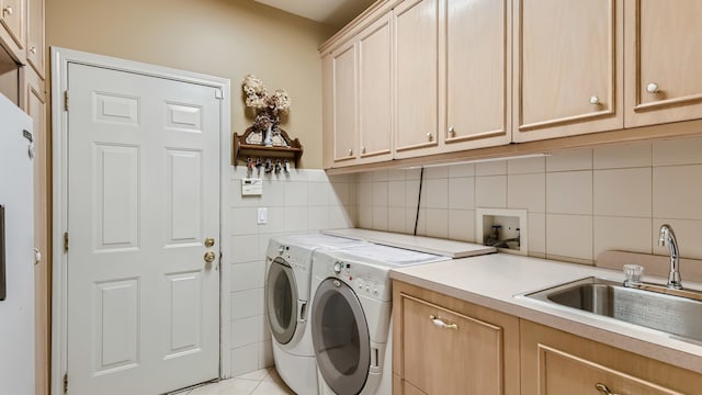 laundry area with washer and dryer, a sink, cabinet space, tile walls, and light tile patterned floors