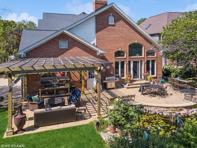 rear view of property with brick siding, an outdoor living space, a chimney, and a patio