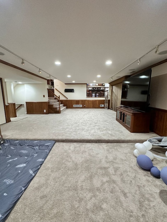 finished basement featuring carpet floors, wood walls, stairs, and visible vents