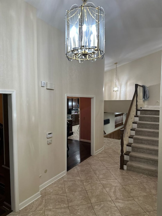 foyer with baseboards, a high ceiling, a chandelier, and stairway