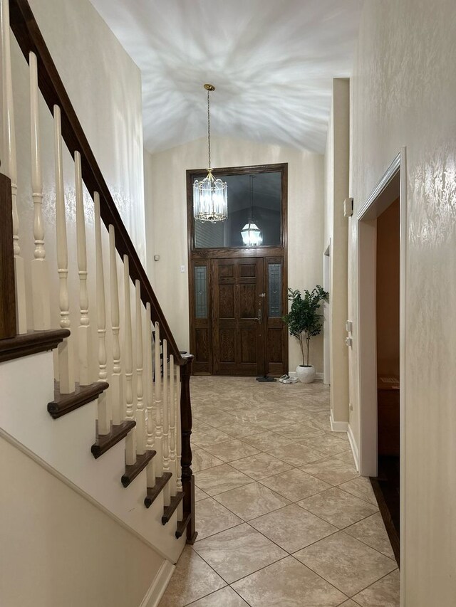 entrance foyer with an inviting chandelier, stairs, and lofted ceiling