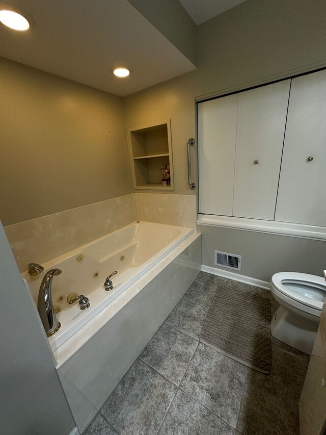 bathroom with toilet, tile patterned floors, built in shelves, a jetted tub, and visible vents