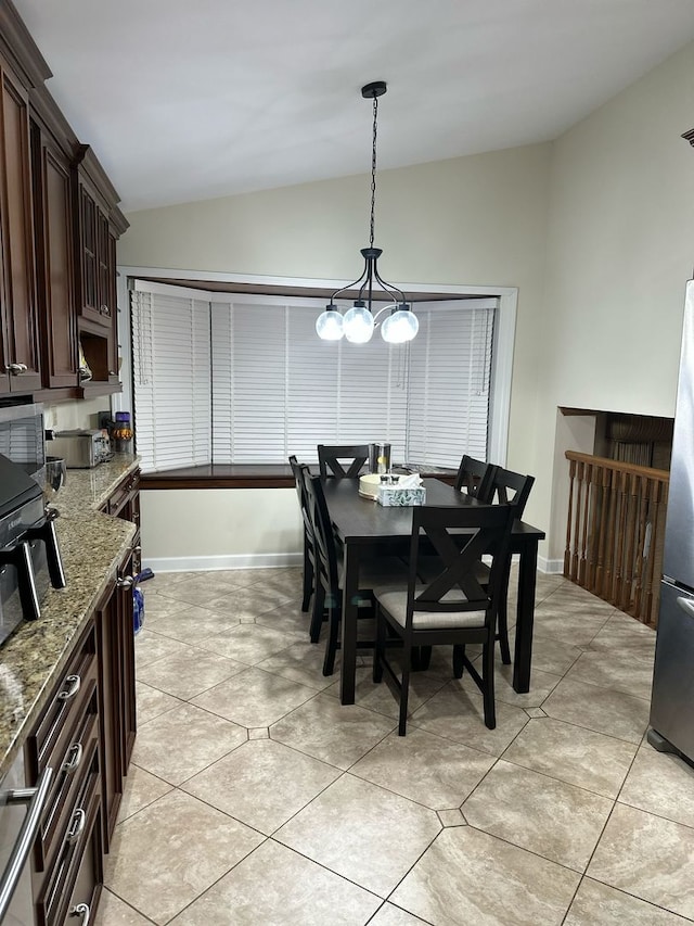 dining room with baseboards, a notable chandelier, light tile patterned floors, and lofted ceiling