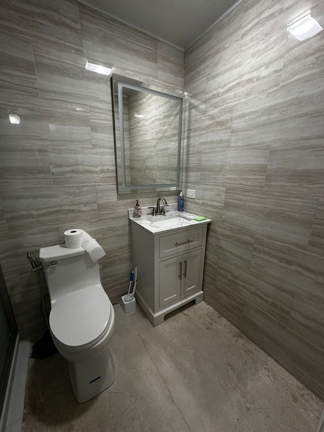 bathroom featuring vanity, toilet, and tile walls