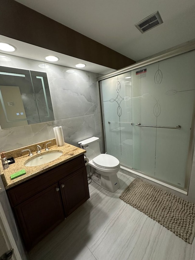 full bath featuring vanity, toilet, tile walls, a shower stall, and visible vents