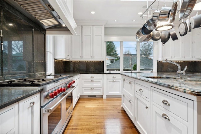 kitchen featuring white cabinets, tasteful backsplash, a sink, and double oven range