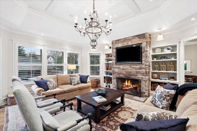 living area featuring wood finished floors, built in shelves, crown molding, an inviting chandelier, and a stone fireplace