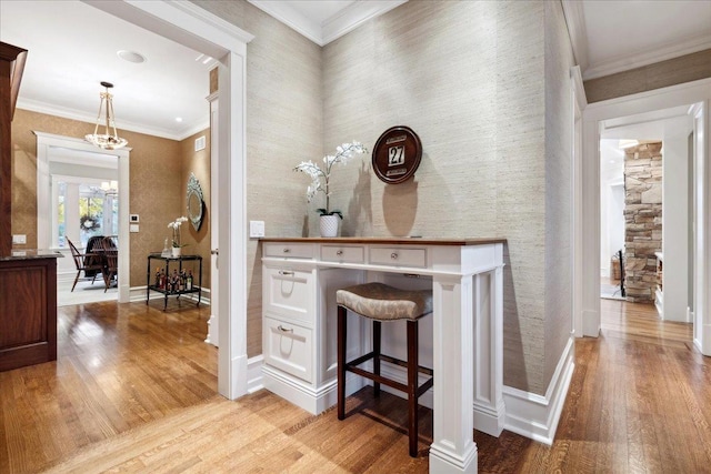 corridor with crown molding, light wood-style flooring, baseboards, and a chandelier