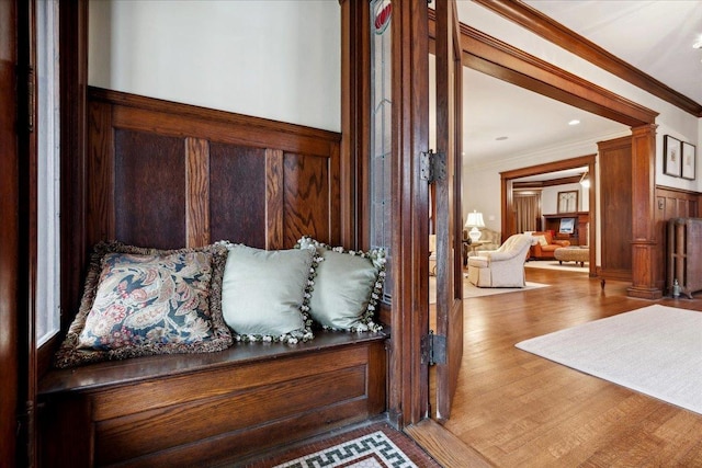 interior space with crown molding, wood walls, wood finished floors, and a wainscoted wall