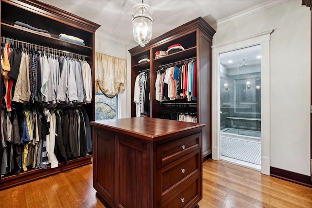 walk in closet featuring light wood-type flooring and a chandelier