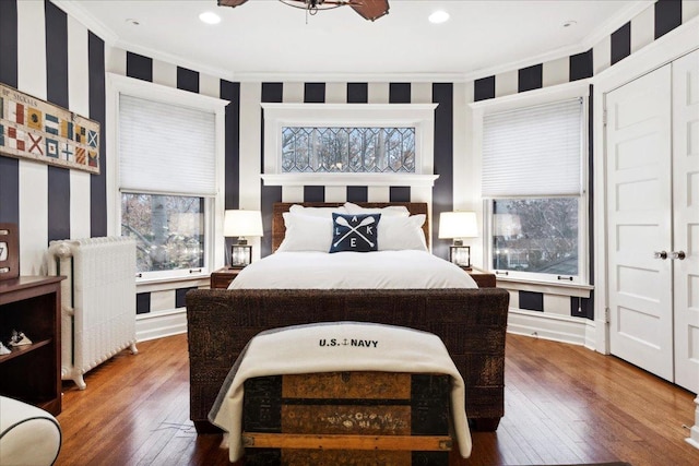 bedroom with hardwood / wood-style flooring, ornamental molding, radiator, and wallpapered walls