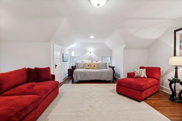 bedroom featuring baseboards, wood finished floors, and vaulted ceiling