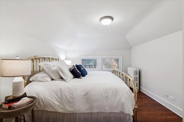 bedroom with vaulted ceiling, wood finished floors, baseboards, and radiator heating unit