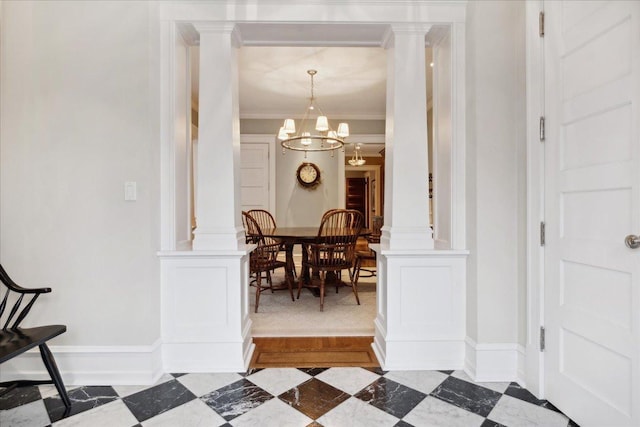 interior space with baseboards, ornamental molding, an inviting chandelier, and decorative columns