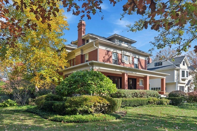 view of front of house with a front lawn, brick siding, and a chimney