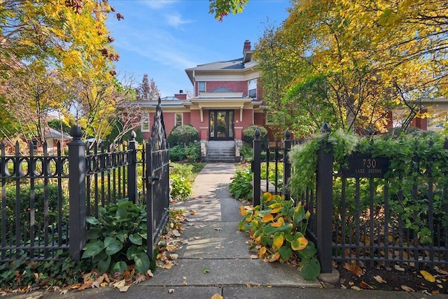 view of front facade with a fenced front yard, brick siding, and a chimney
