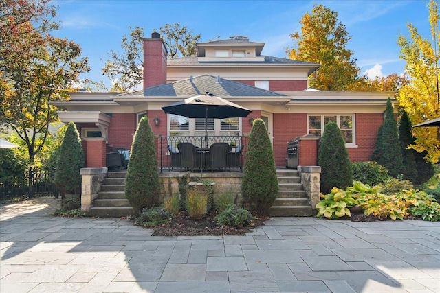 traditional style home featuring a wooden deck, a chimney, and brick siding