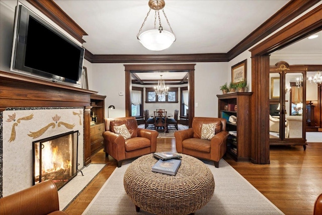 living room with a high end fireplace, an inviting chandelier, crown molding, and wood finished floors