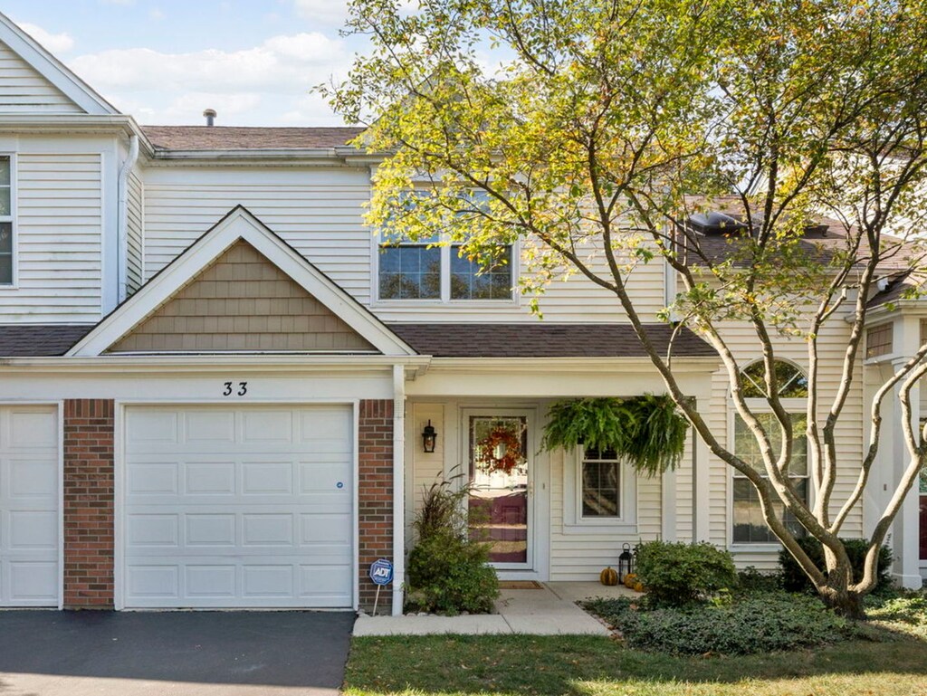 33 Marion Ln, Streamwood, IL 60107 - multi unit property featuring an attached garage, brick siding, roof with shingles, and driveway