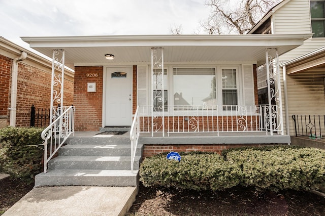 property entrance featuring brick siding and covered porch