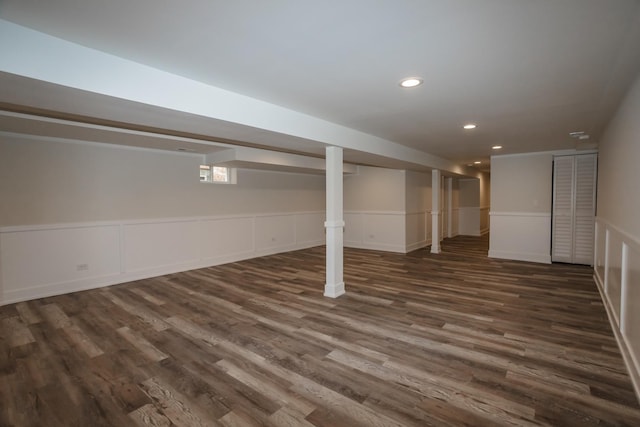 finished below grade area featuring dark wood-style floors, recessed lighting, and wainscoting