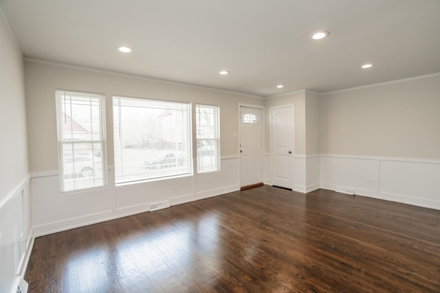 spare room with dark wood finished floors, crown molding, a wainscoted wall, and visible vents
