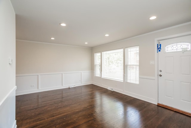 foyer entrance featuring dark wood finished floors, wainscoting, and ornamental molding