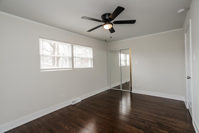 unfurnished bedroom featuring visible vents, baseboards, ornamental molding, and dark wood-style flooring