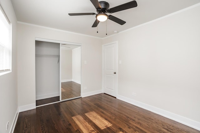 unfurnished bedroom featuring dark wood-type flooring, crown molding, baseboards, and a closet