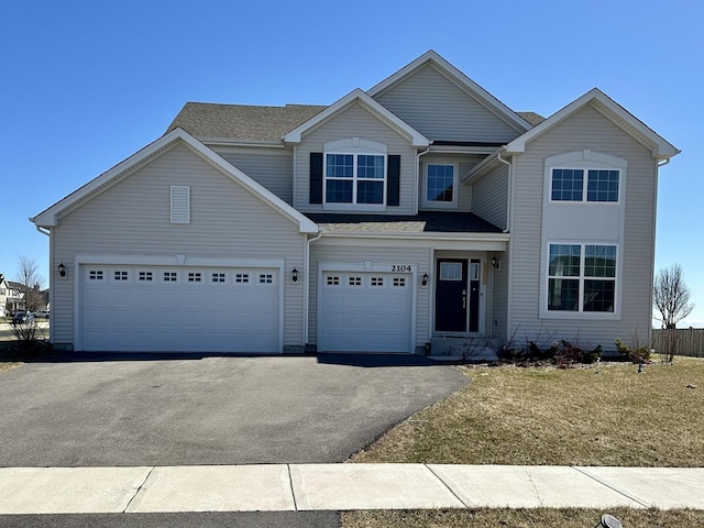 traditional home featuring aphalt driveway, an attached garage, and a shingled roof