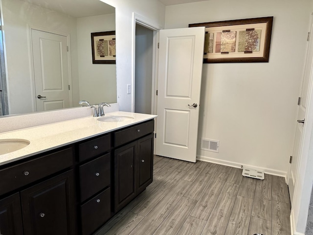 bathroom featuring double vanity, wood finished floors, visible vents, and a sink