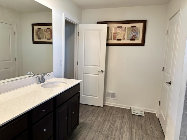 bathroom featuring visible vents, vanity, baseboards, and wood finished floors