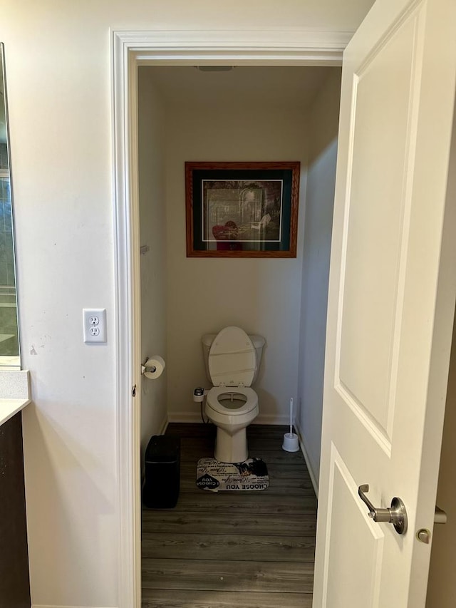 bathroom with toilet, wood finished floors, and baseboards
