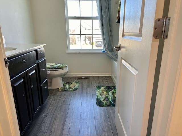 bathroom featuring visible vents, toilet, hardwood / wood-style flooring, baseboards, and vanity
