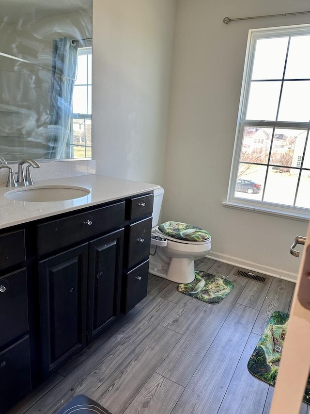 bathroom with visible vents, toilet, wood finished floors, baseboards, and vanity
