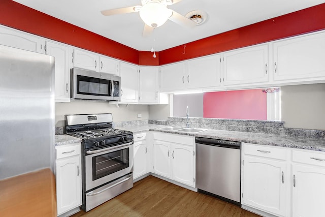 kitchen featuring light countertops, stainless steel appliances, wood finished floors, white cabinetry, and a sink