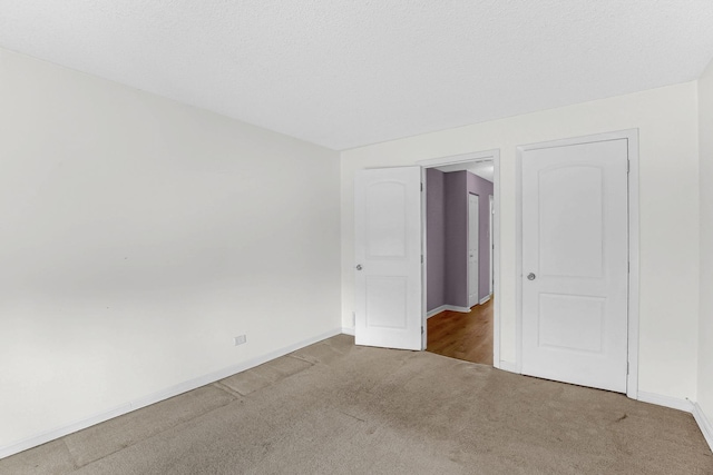 unfurnished room with carpet flooring, baseboards, and a textured ceiling