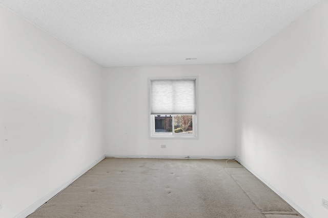 empty room featuring carpet flooring, a textured ceiling, and baseboards