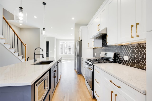 3502 S Union Ave, Chicago, IL 60609 - kitchen with appliances with stainless steel finishes, under cabinet range hood, a sink, white cabinetry, and tasteful backsplash